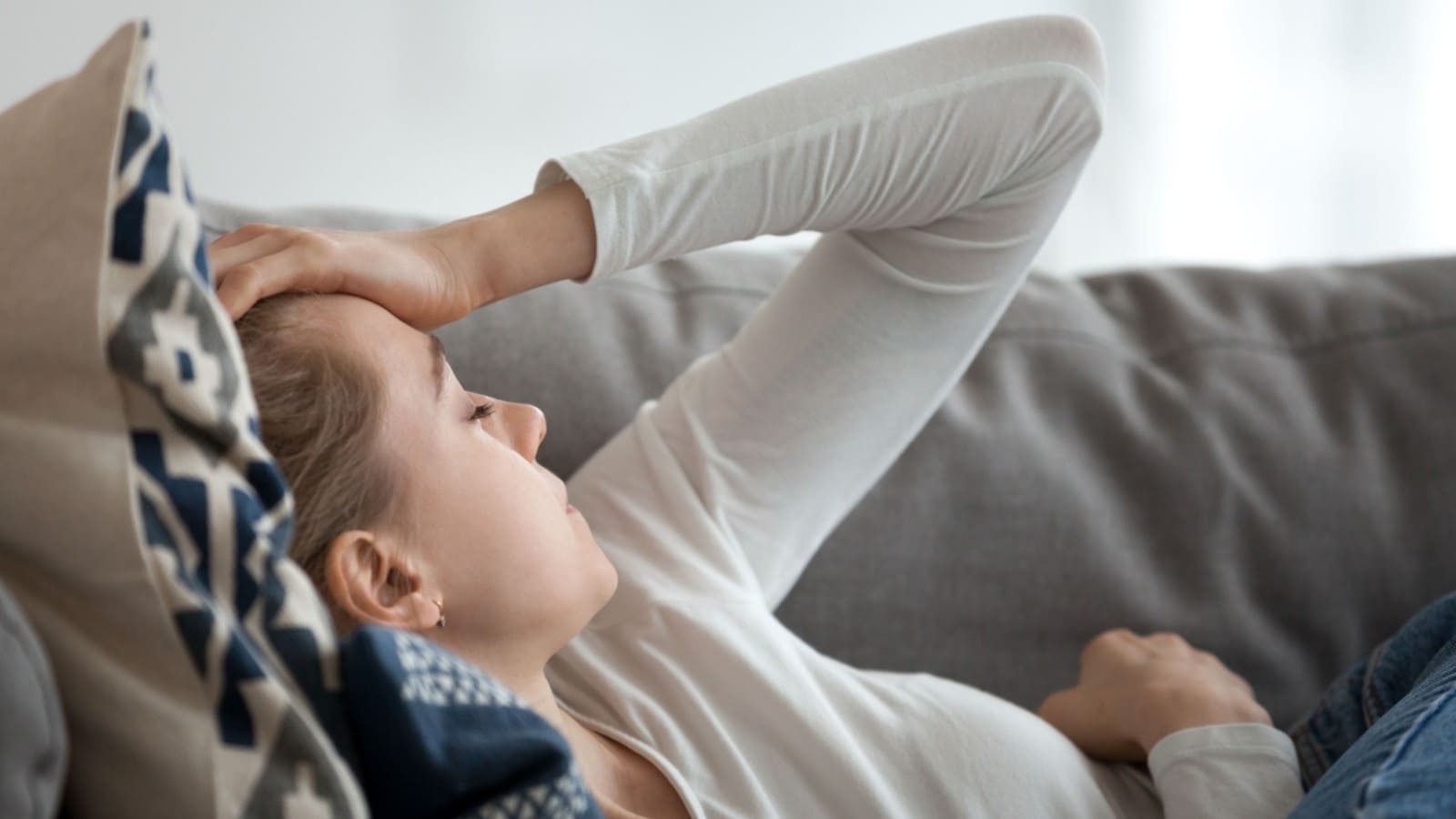 Young woman lying on the couch with a headache