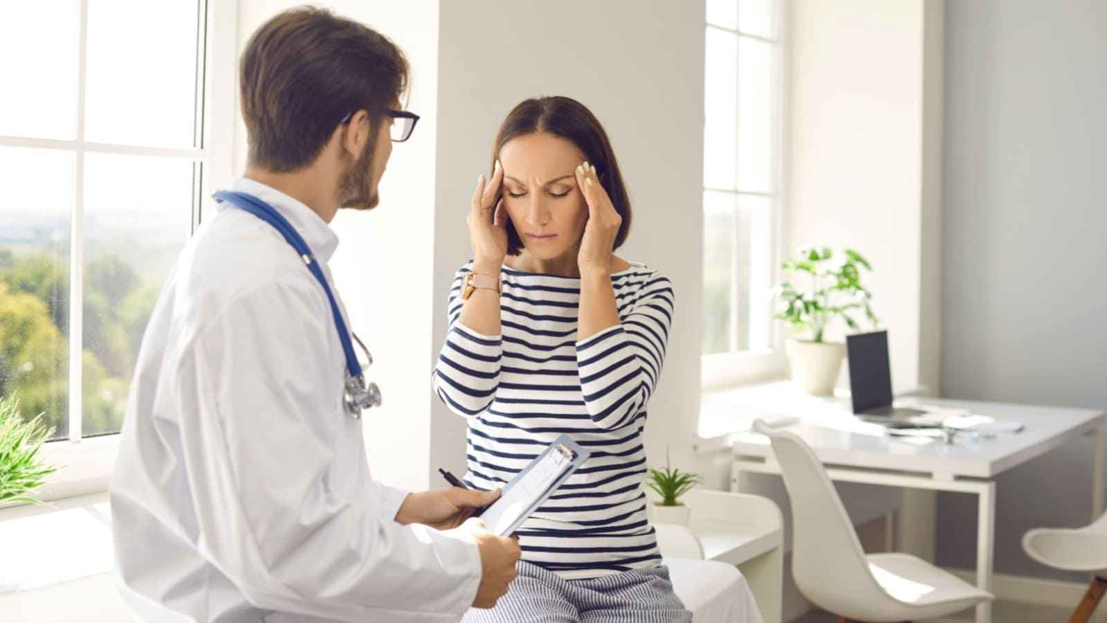 Male doctor checking woman with migraine