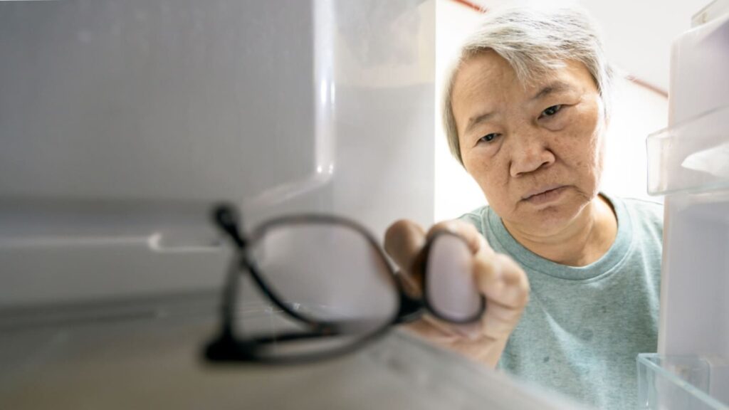 Old woman putting eyeglasses in the refrigerator
