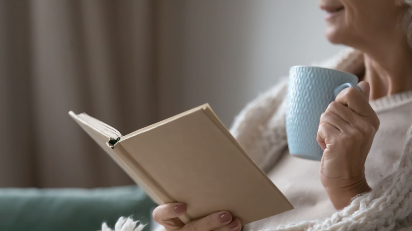 Senior woman reading while holding a mug