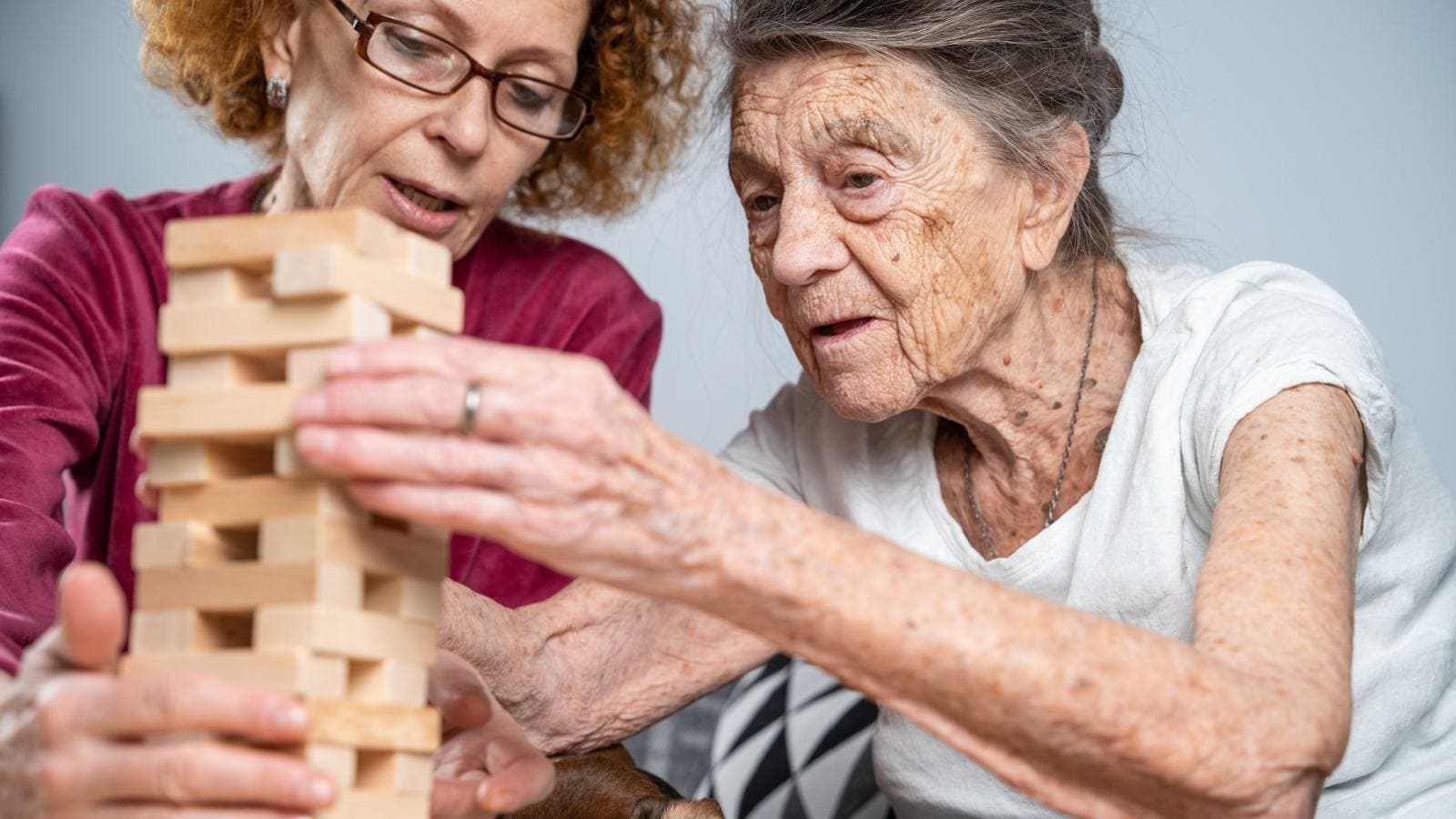 Old woman and a social worker playing jenga as a dementia therapy