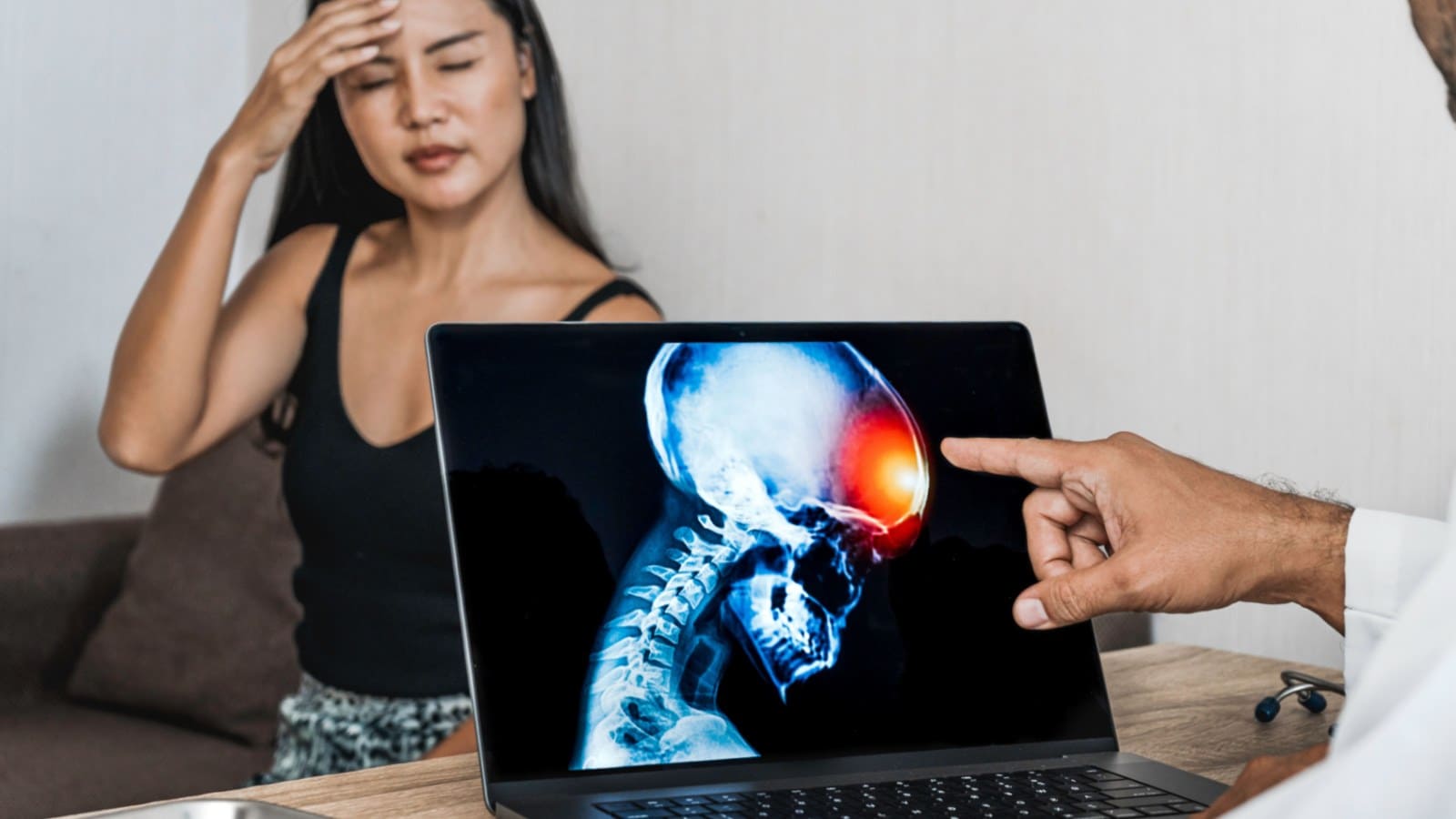 Woman with a headache and a doctor with a laptop wit an xray result