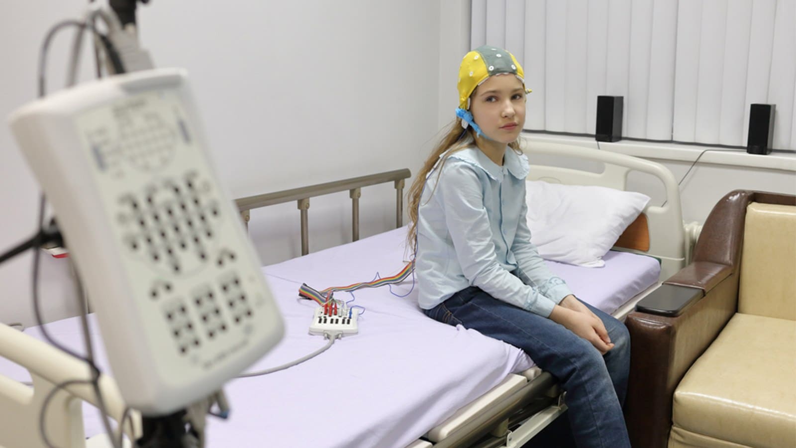 Young girl sitting on the bed on an EEG test